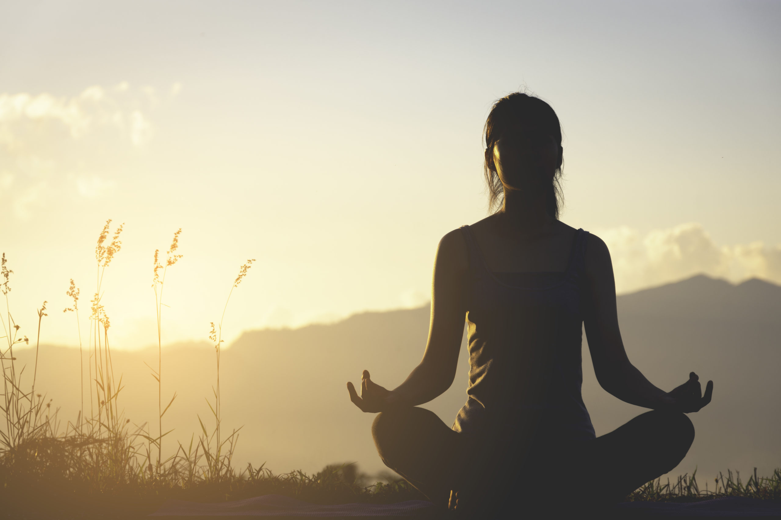 silhouette fitness girl practicing yoga on mountain with sun light